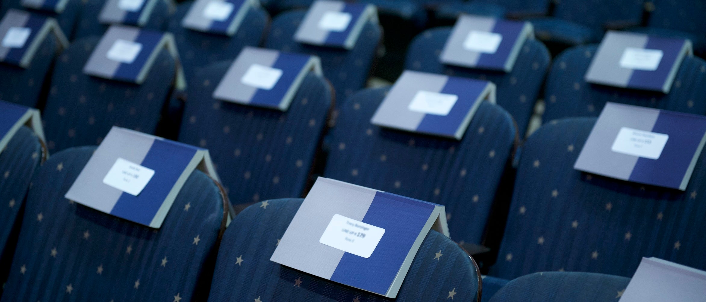 Rows of chairs with commencement booklets laid out on them.