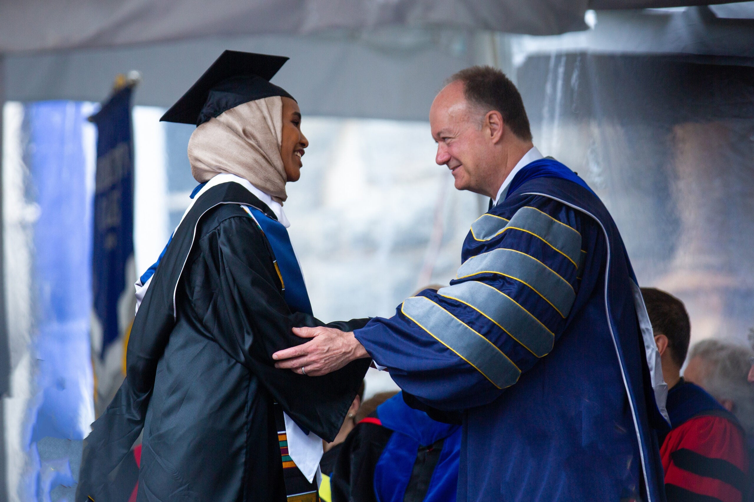 A graduate shakes hands with President DeGioia on the commencement stage.