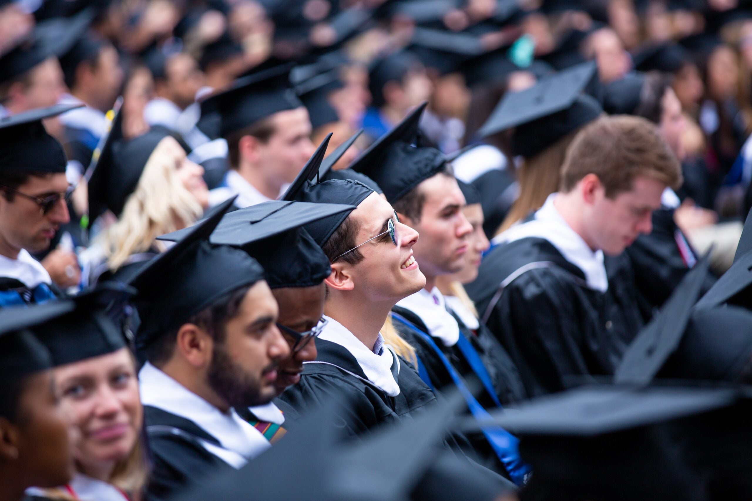 A crowd of graduates at a commencement ceremony, wearing caps and gowns.